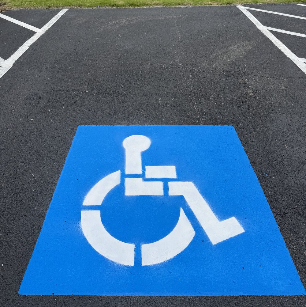 Crisp blue and white ADA wheelchair symbol painted on asphalt parking space